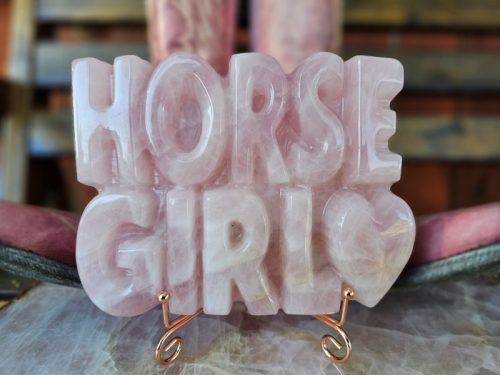 Horse Girl carving displayed on rose-gold stand with riding boots in background